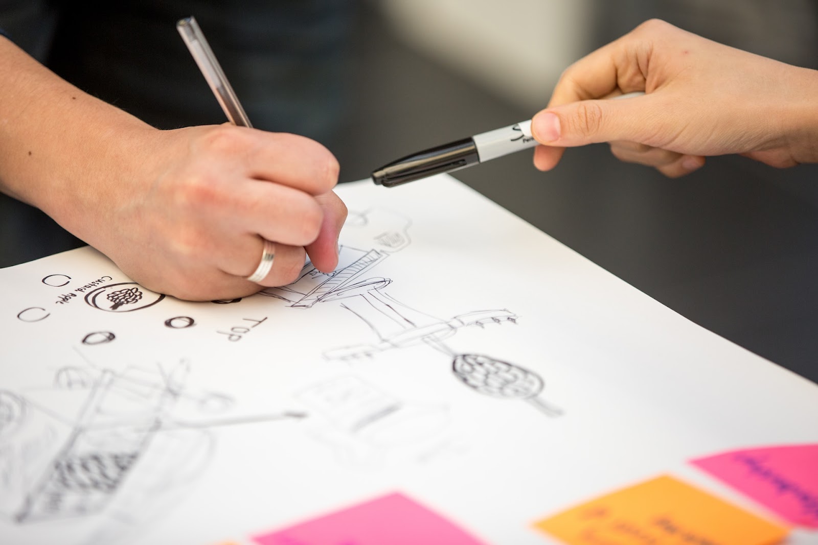 Two people brainstorming and drawing on a piece of paper. 